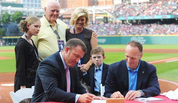 Aug 2, 2014; Cleveland, OH, USA; Surrounded by his family, Cleveland Indians former player Jim Thome signs a one-day contract with Cleveland Indians president Mark Shapiro before the game between the Cleveland Indians and the Texas Rangers at Progressive Field. Ken Blaze-USA TODAY Sports