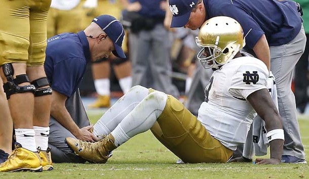 Sep 12, 2015; Charlottesville, VA, USA; Notre Dame Fighting Irish quarterback Malik Zaire (8) is examined by team trainers after injuring his right ankle against the Virginia Cavaliers in the third quarter at Scott Stadium. The Fighting Irish won 34-27. Mandatory Credit: Geoff Burke-USA TODAY Sports